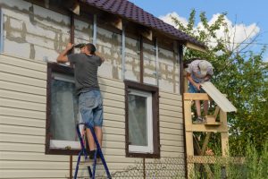 Workers replacing home with new vinyl siding